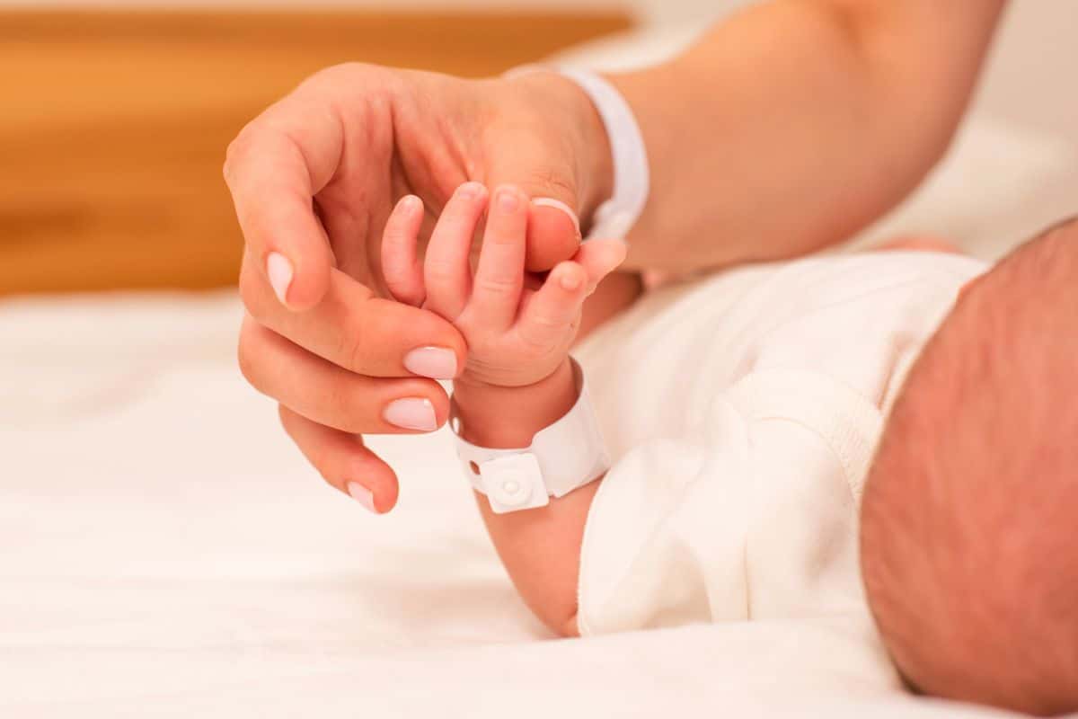 Person holding a baby's hand wearing a hospital bracelet
