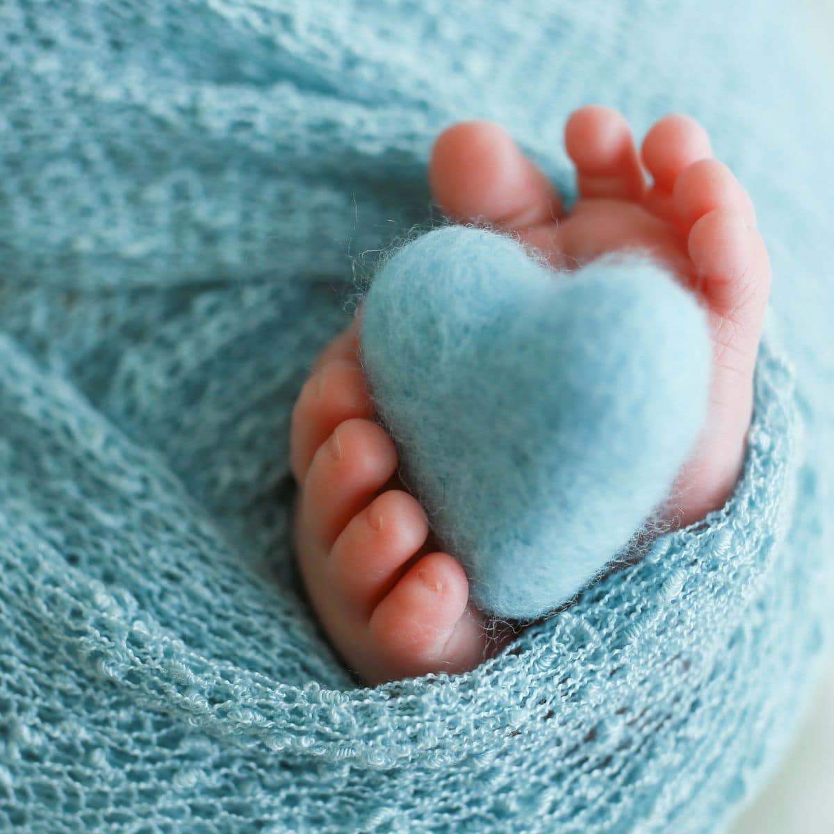 Baby feet wrapped in blue blanket with hearts