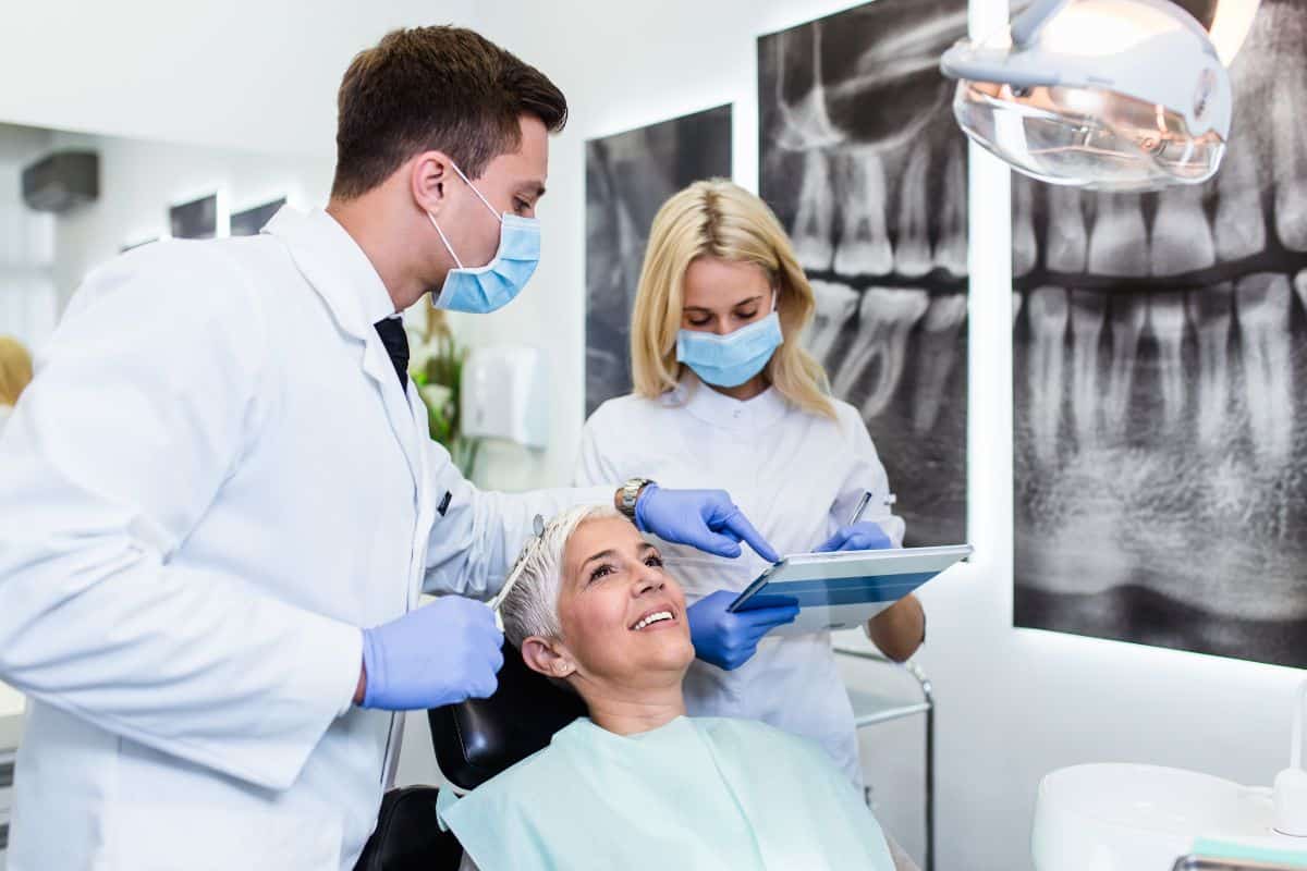 Patient sitting in chair while dentists look over their records
