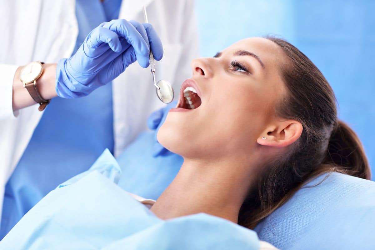 Dentist holding small mirror into patients mouth