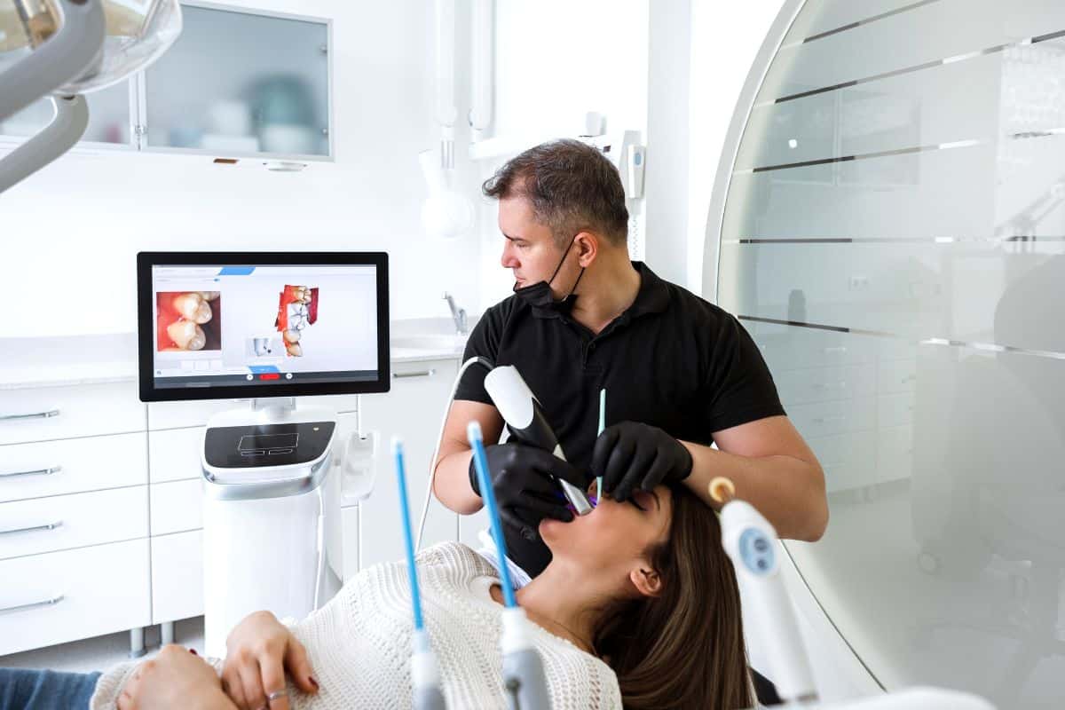 Dentist using dental technology machine on patient to look at teeth on computer