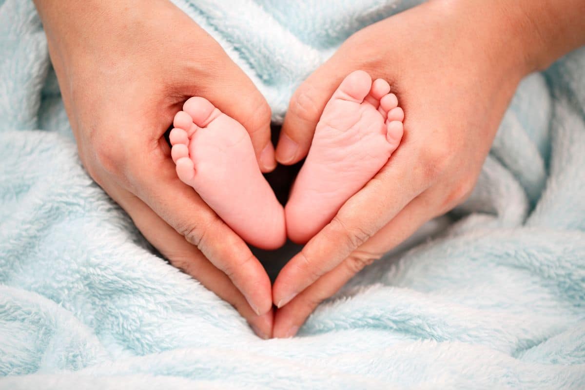 Person holding baby feet in the shape of a heart
