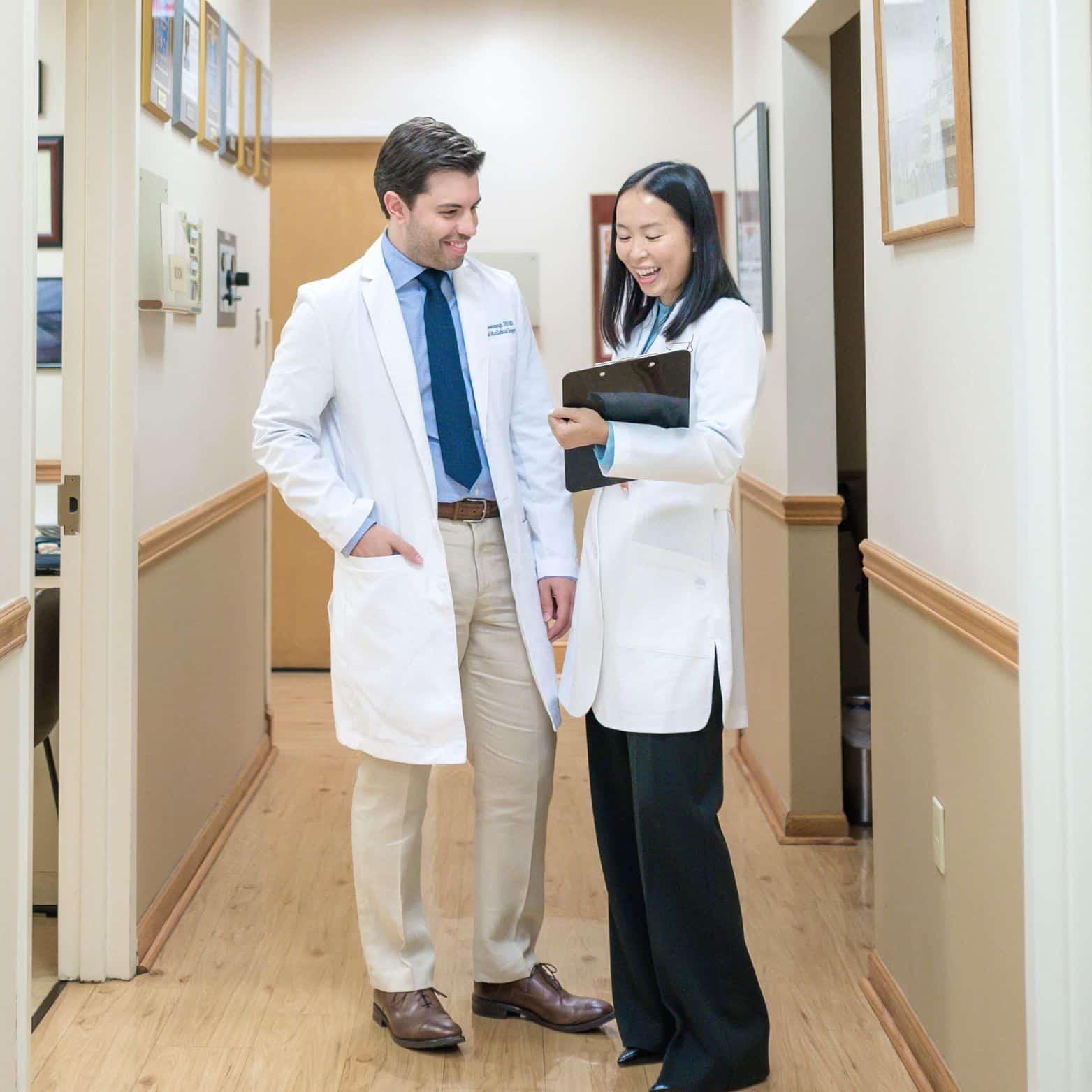 Dentists standing and talking while looking at clipboard